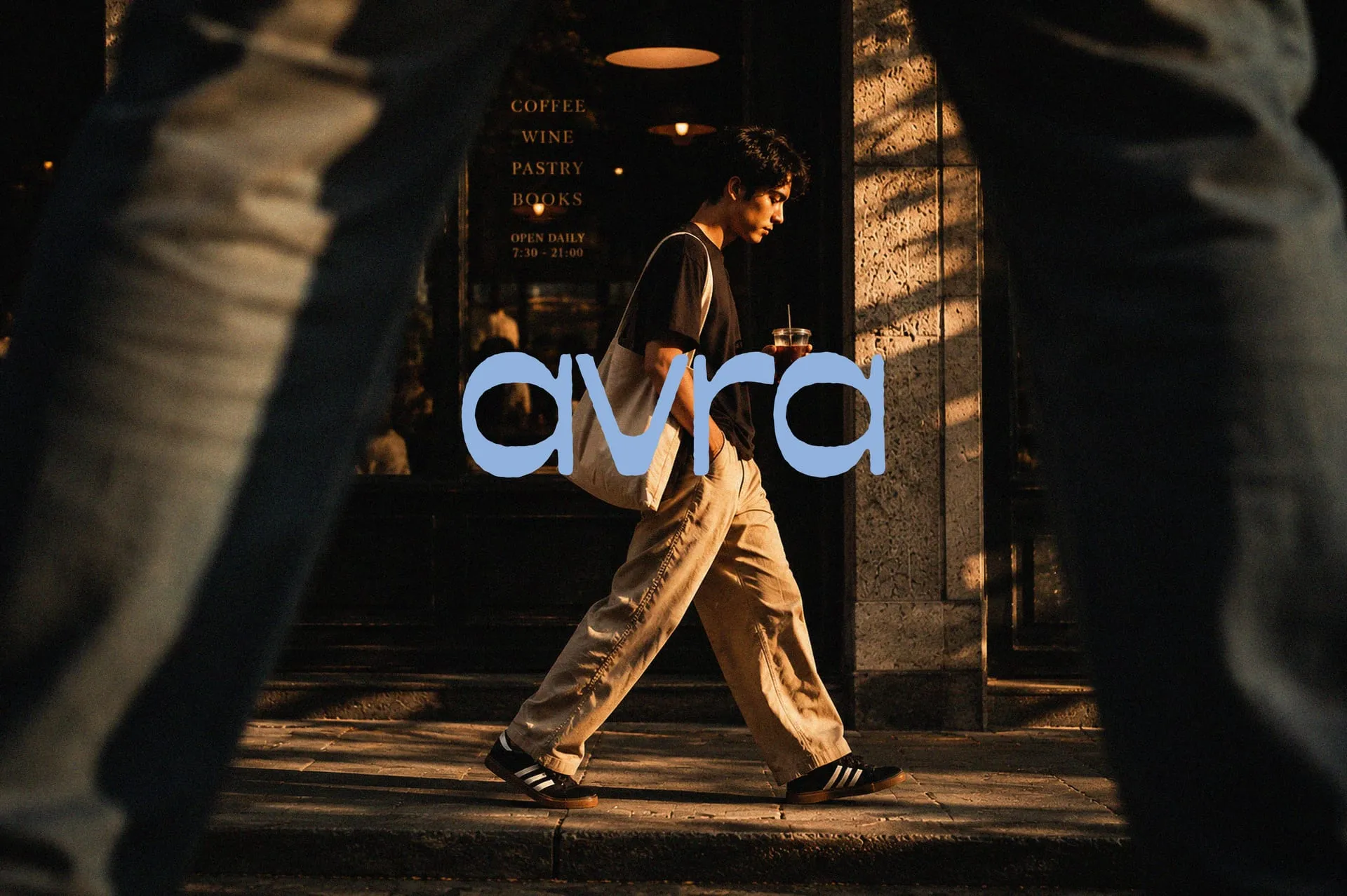 Persona caminando con sneakers frente a una cafetería, con el logo de AVRA